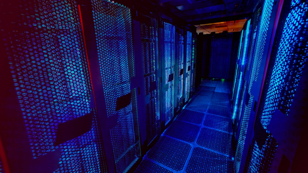 Pasillo de un centro de datos entre gabinetes, iluminado en azul